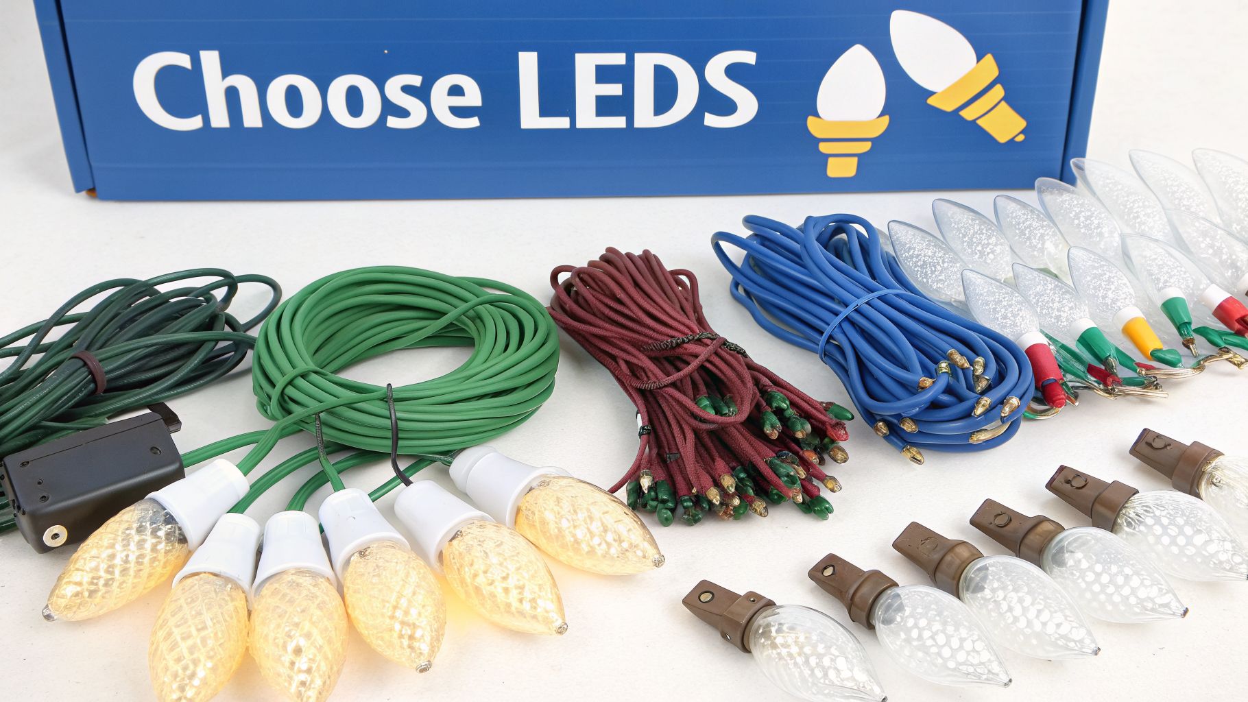 Assortment of colorful LED Christmas light bulbs, wires, and sockets on a white surface.