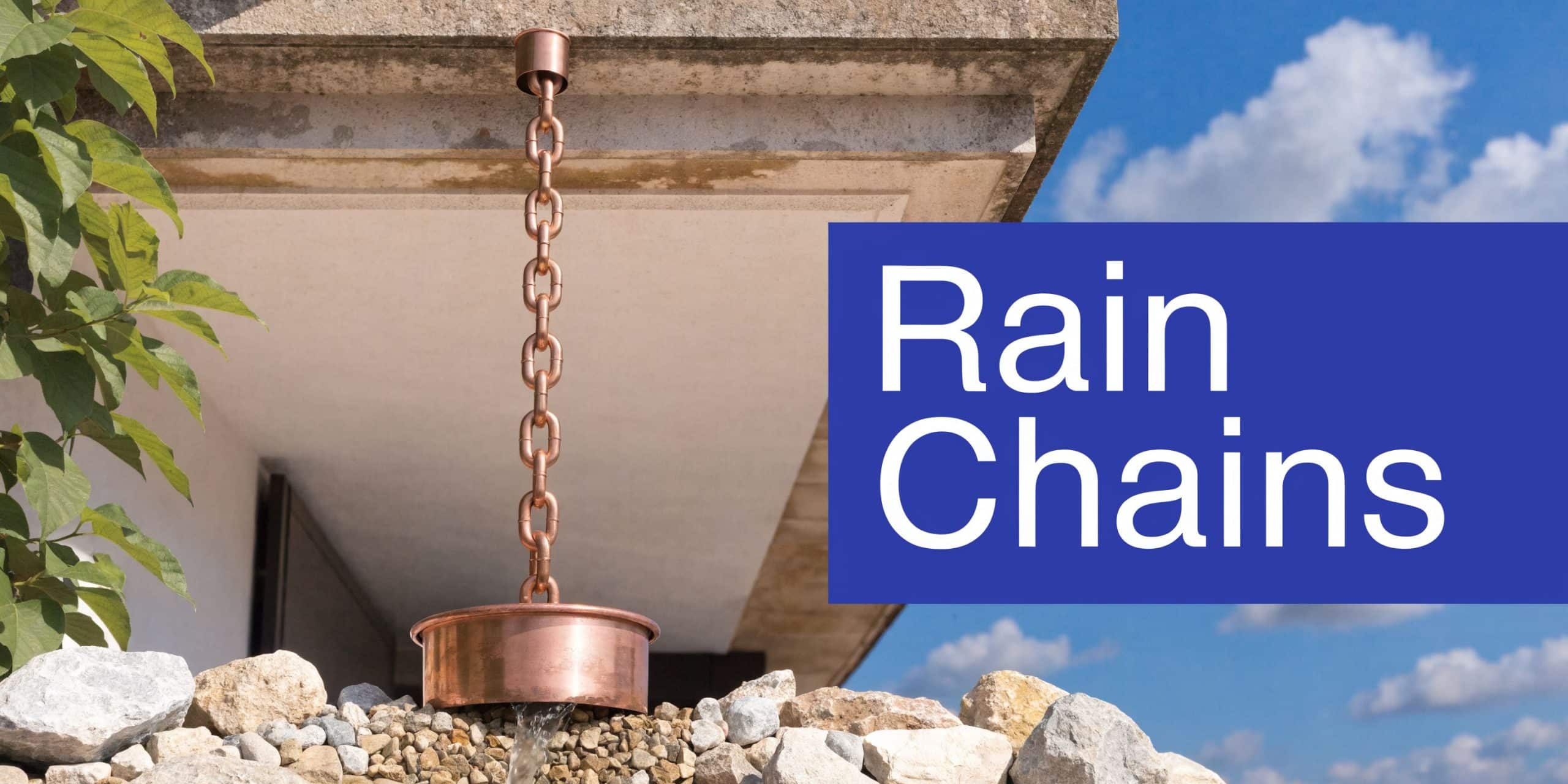 A copper rain chain hanging from a modern house roof, leading water into a stone-filled decorative basin.