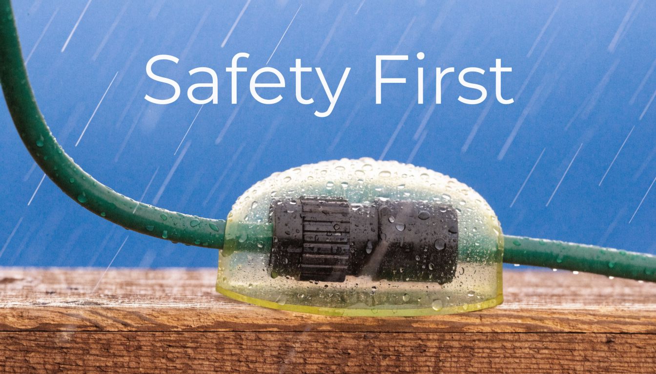 A weather-resistant outdoor power cord connector box protecting plug connections on a wooden surface in rain.
