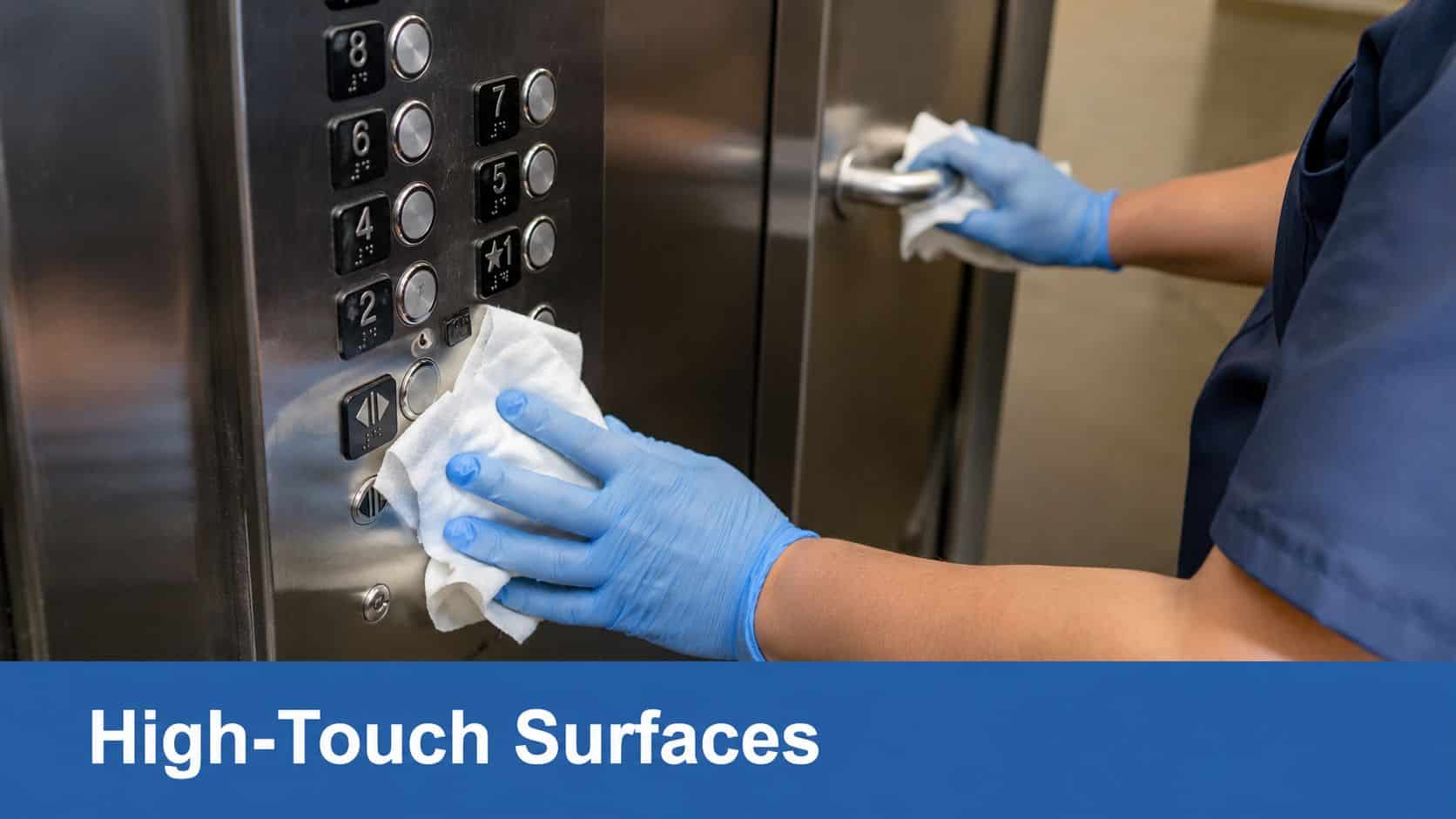 A person wearing blue gloves wipes down elevator buttons and a handle with a cleaning cloth.